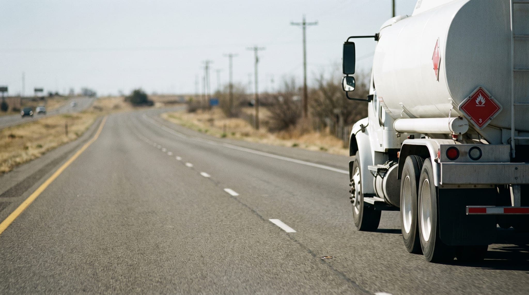 Placarded tanker truck on an empty interstate at dawn